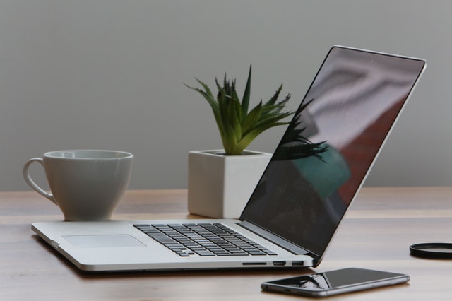 Silver laptop and white cup on table